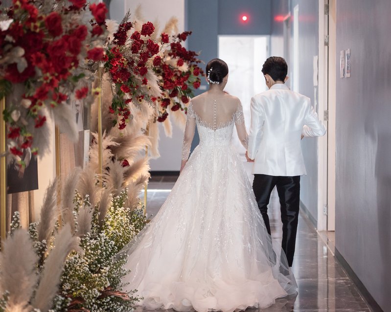 Bride and groom walking along a flower-lined corridor