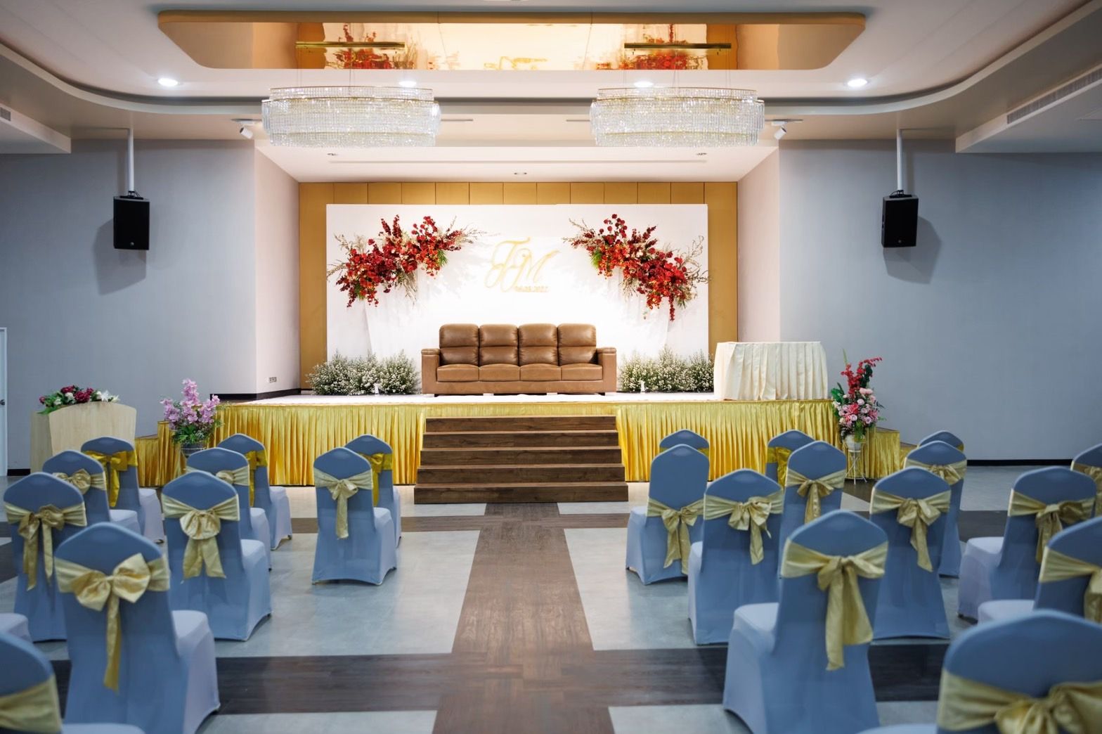 Ballroom stage set for a wedding with red floral backdrop
