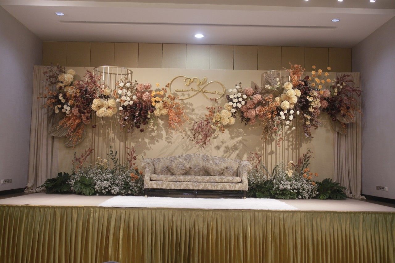 Floral wedding backdrop in autumn tones with a sofa for the couple