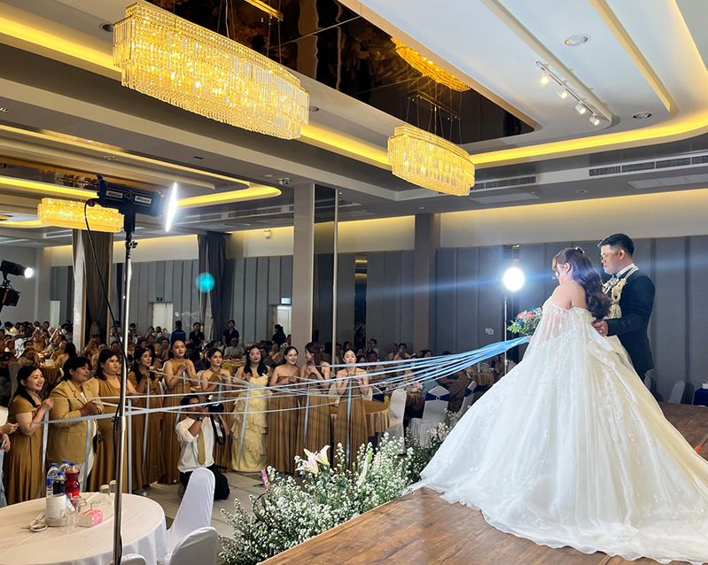 Bride and groom on stage in front of a full ballroom of guests