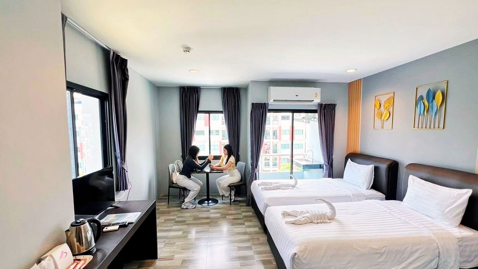 Twin room with two guests at a small table by the window