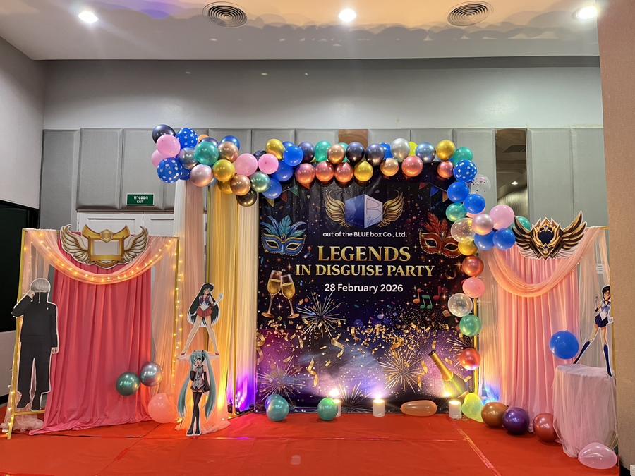 Themed photo backdrop decorated with balloons and masks