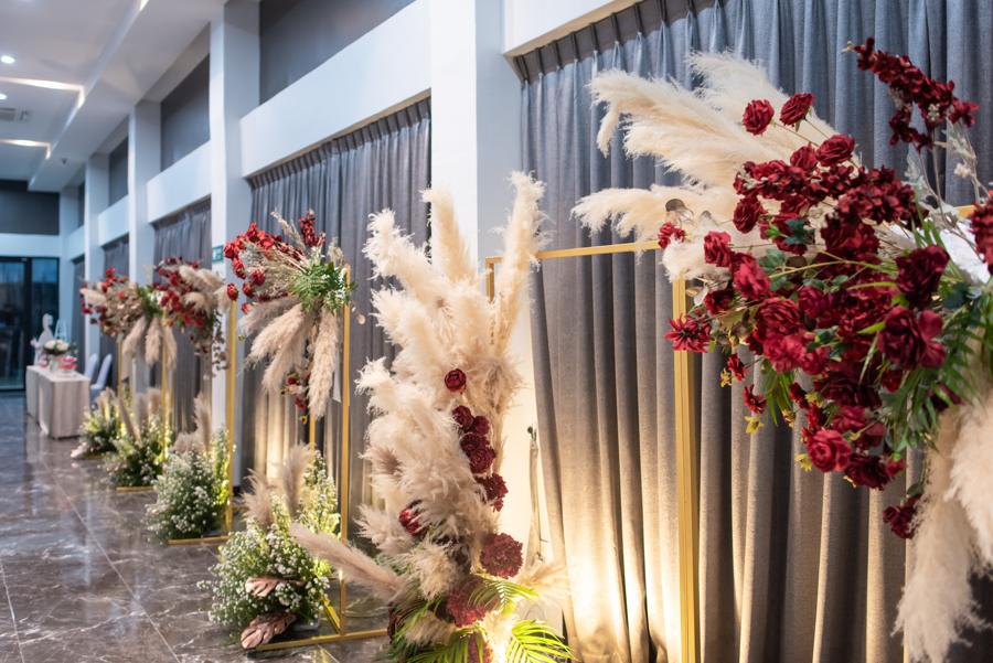 Corridor lined with pampas grass and red rose arrangements