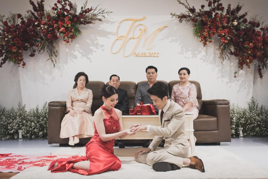 Couple exchanging rings in front of their parents during the Thai engagement ceremony