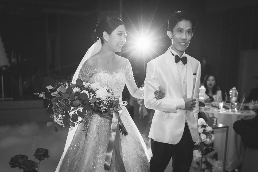 Black-and-white photo of the bride and groom arriving arm in arm