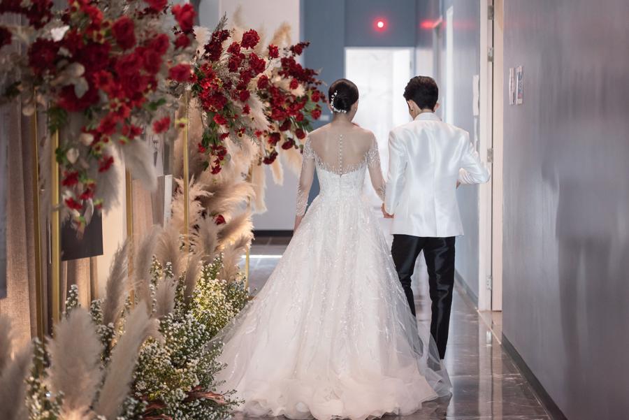 Bride and groom walking along a flower-lined corridor