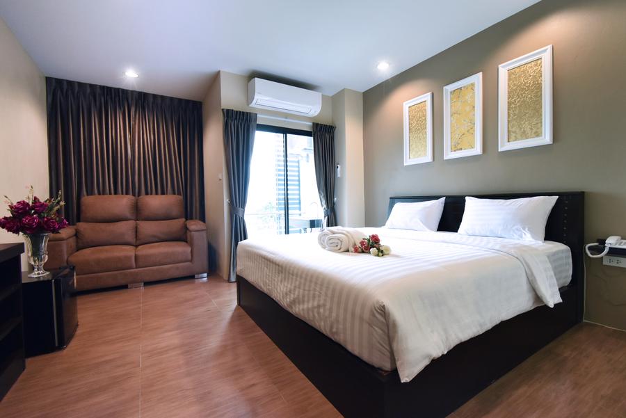 Deluxe room with a double bed, leather sofa and fresh flowers