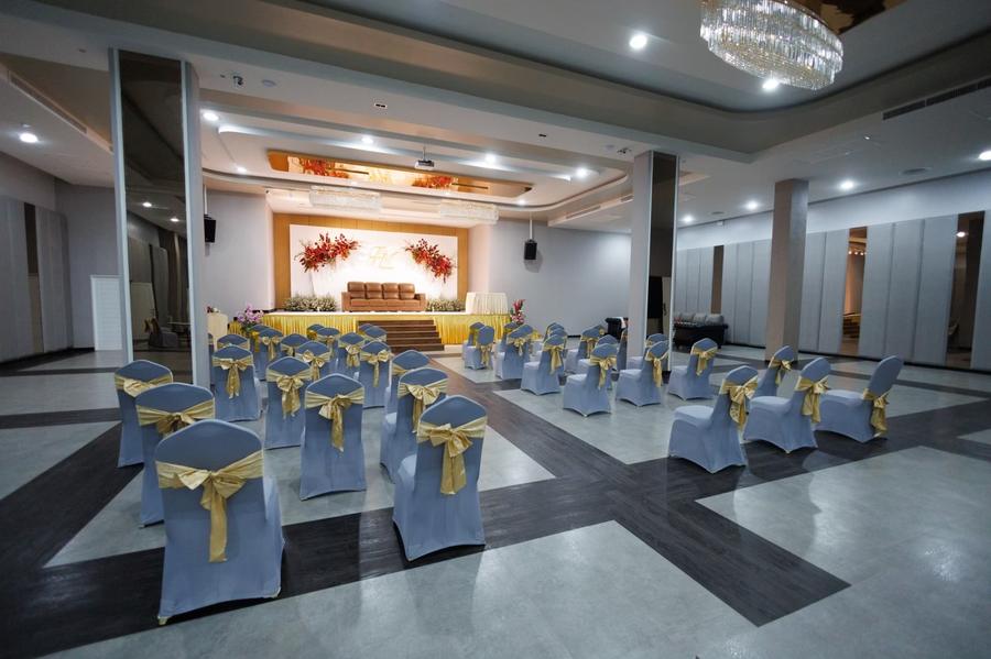 Ballroom set for a wedding with gold-sashed chairs