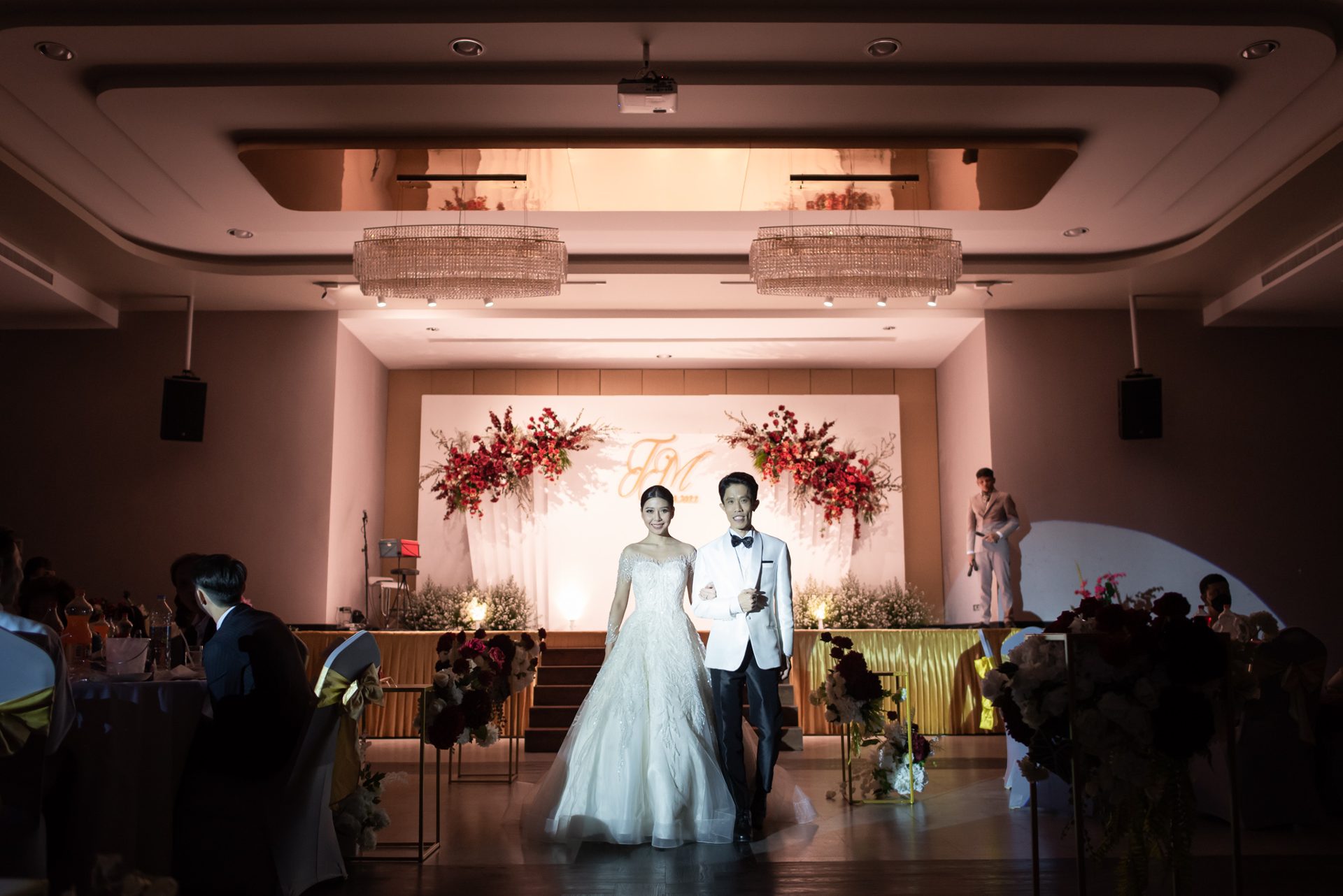 Bride and groom making their entrance in front of the floral wedding stage in the ballroom