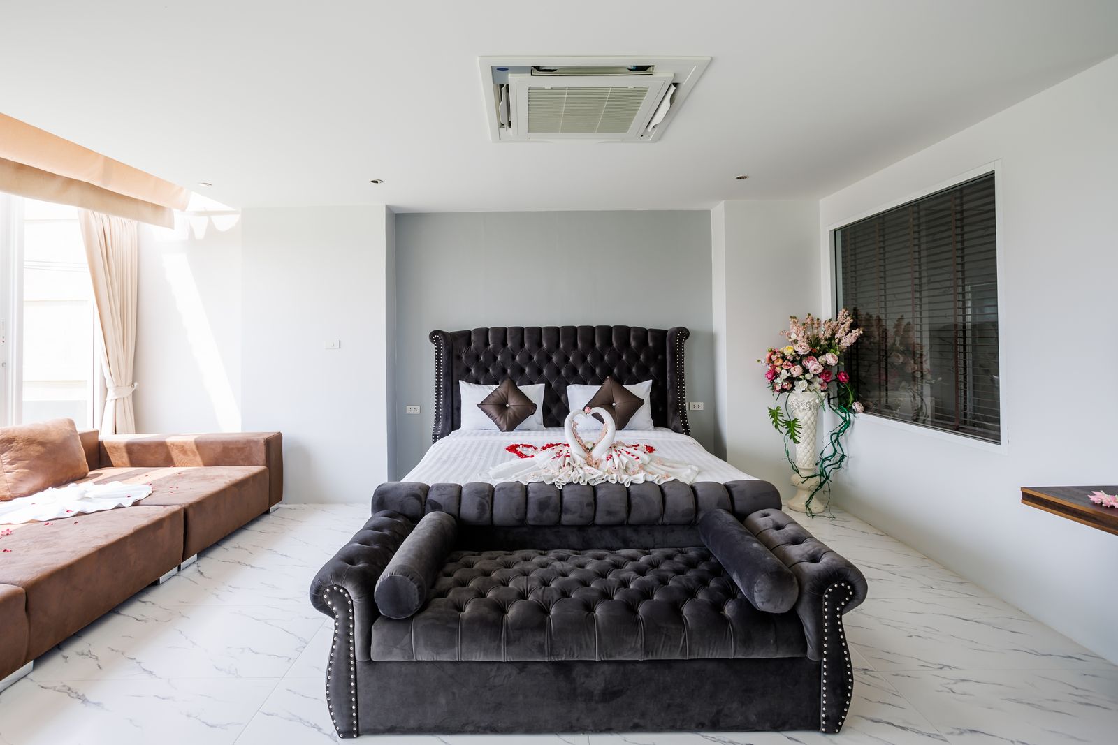 Honeymoon suite with tufted bed, chaise sofa and flowers
