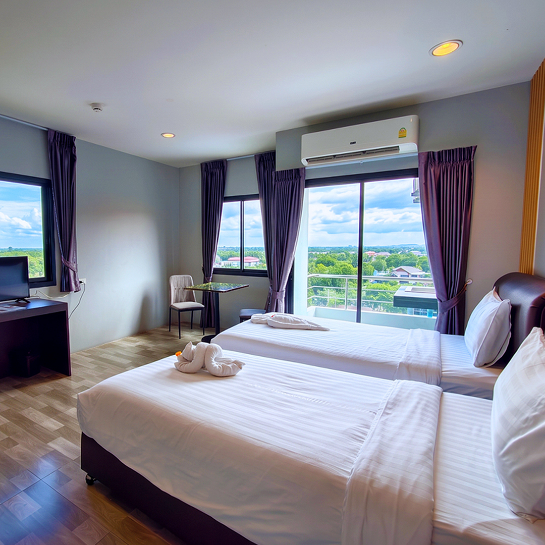 Twin room with crisp white beds and a balcony overlooking green countryside